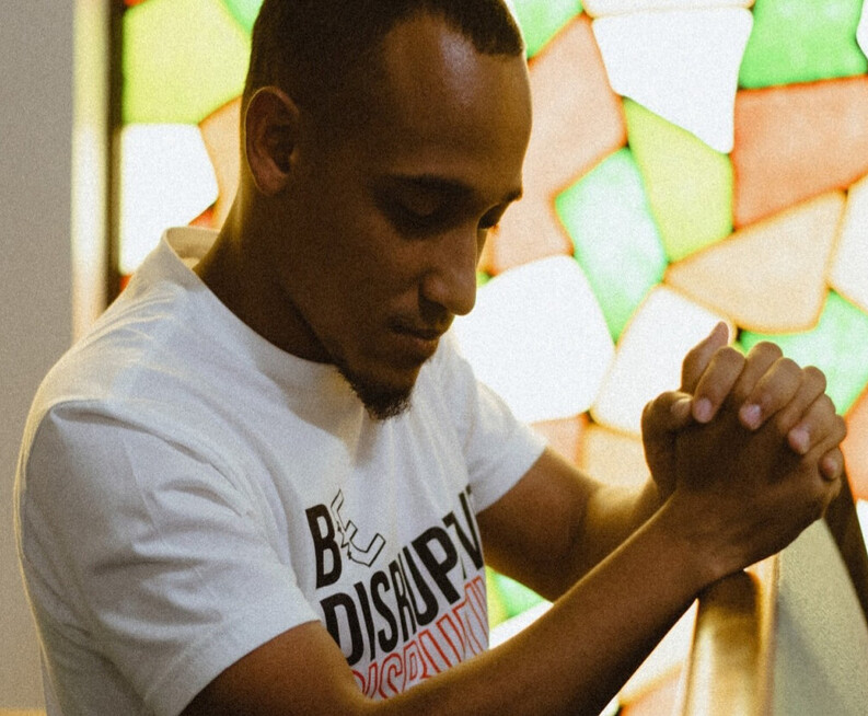 Man kneeling in church pew praying