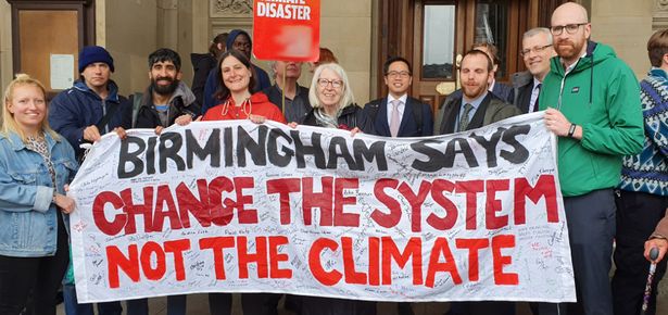 Group of people holding up a sign that reads 'Birmingham says change the system not the climate