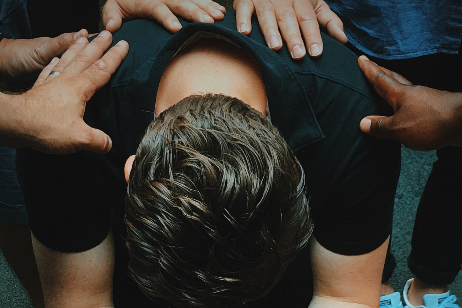 Image of man with people praying for him